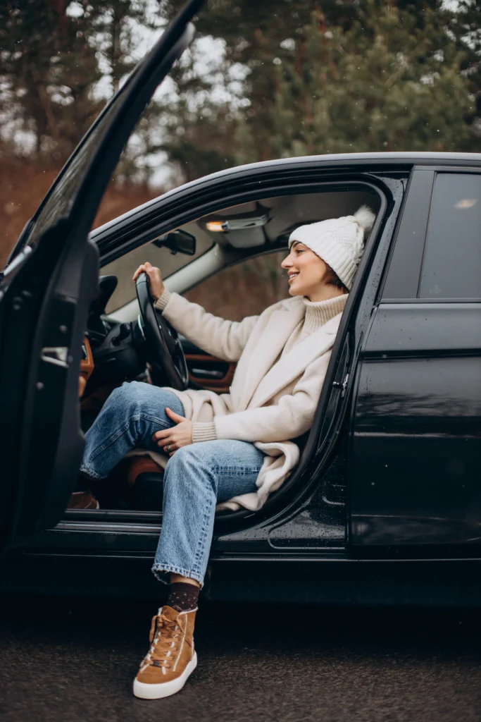 Une cliente en manteau d'hiver assise au volant de sa voiture.